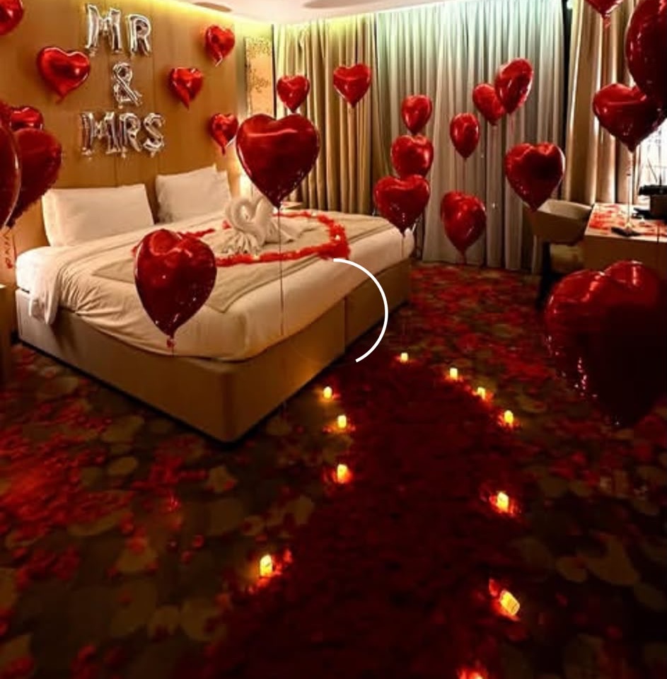 Red heart balloons and rose petals styled for an anniversary room