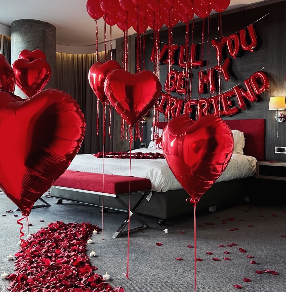 Red heart balloons and rose petals in a Radisson Blu hotel room